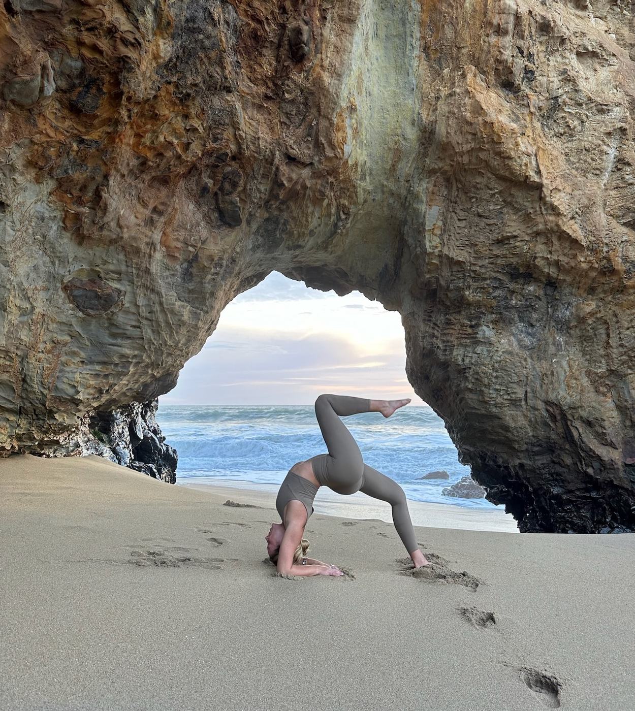 Macy holding a pose beneath a sea arch